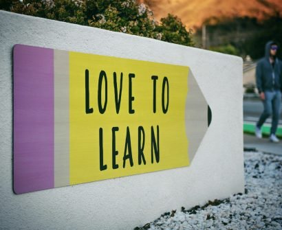 love to learn pencil signage on wall near walking man